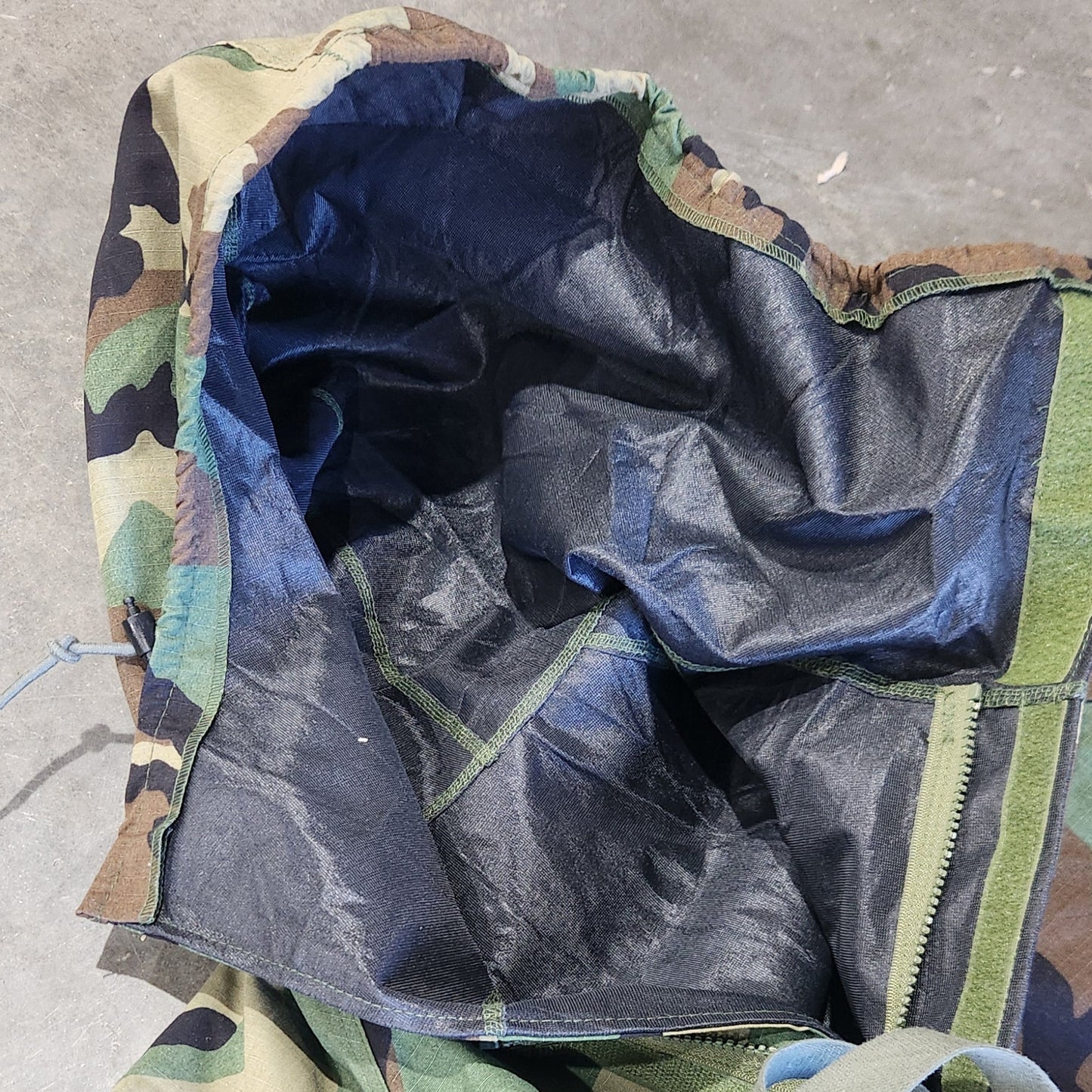 Camouflage jacket hood with a black interior lining on a concrete surface
