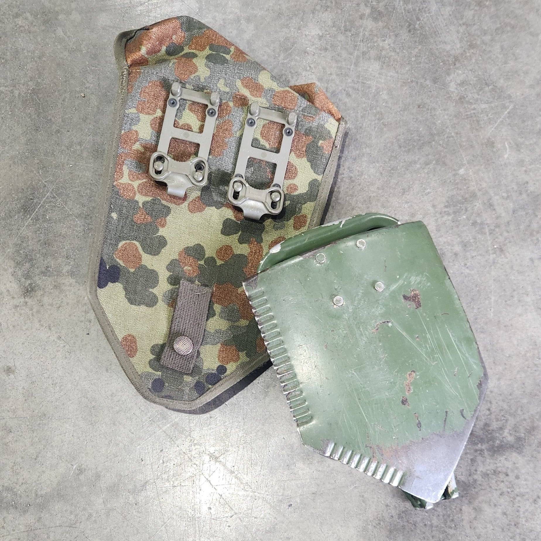 Two camouflage-patterned metal devices on a concrete floor.